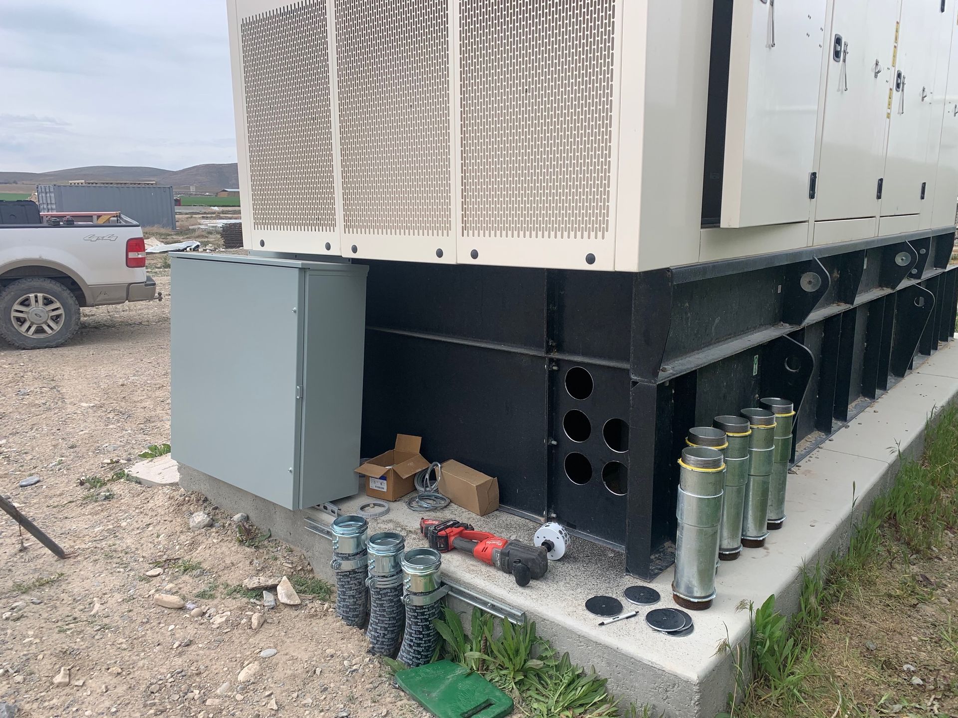 Generator unit with electrical components, gray enclosure, outdoors.