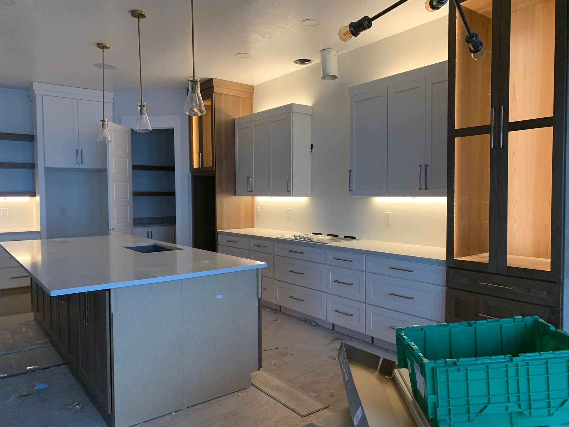 Modern kitchen with white cabinets, wood accents, island, and green bin.