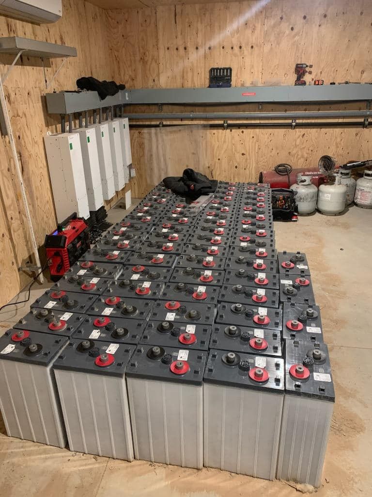 Batteries in a room, likely for energy storage. Gray batteries in rows with other equipment on the walls.