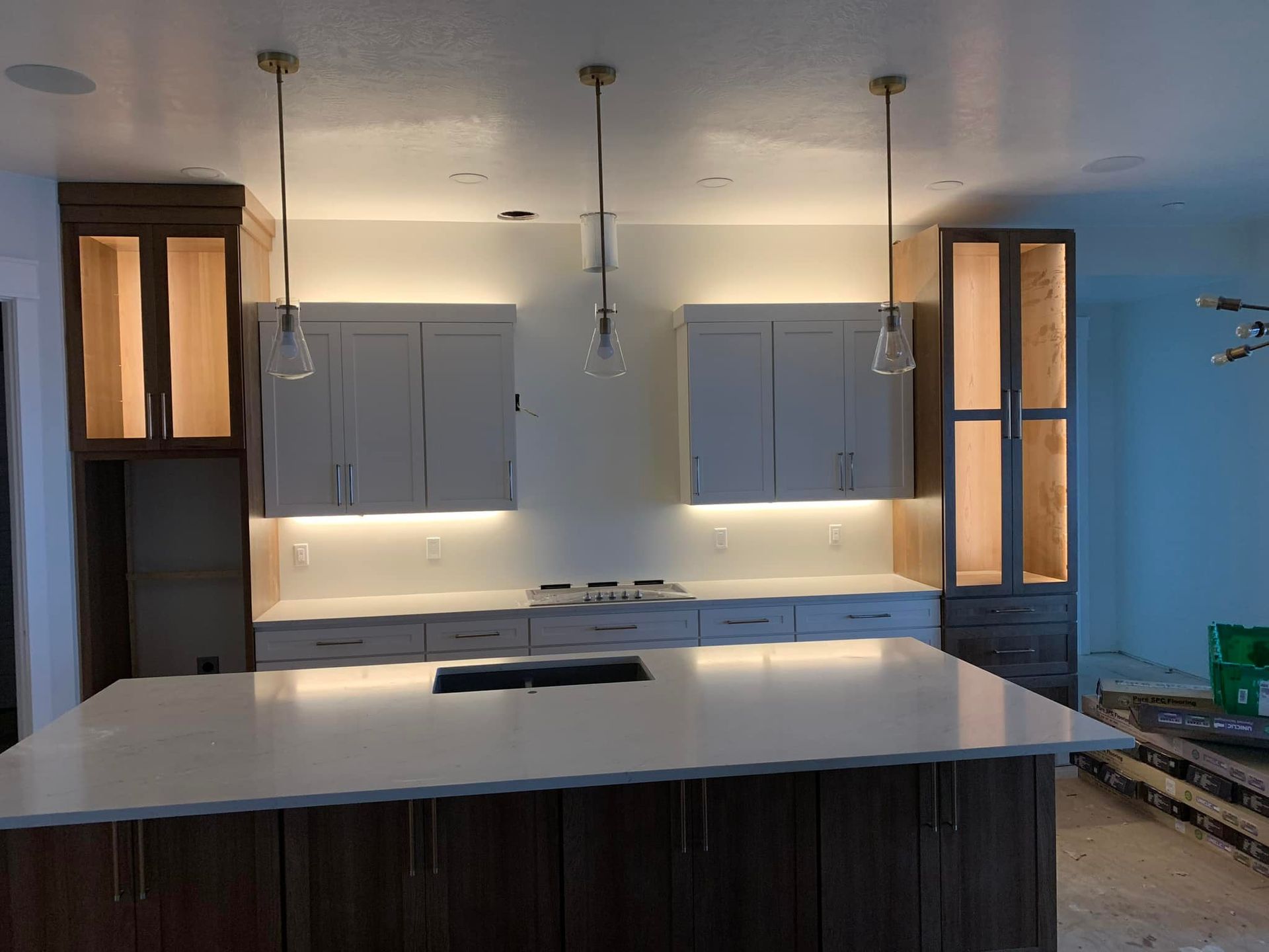 Kitchen with white countertops, light cabinets, island, pendant lights, and built-in appliances.
