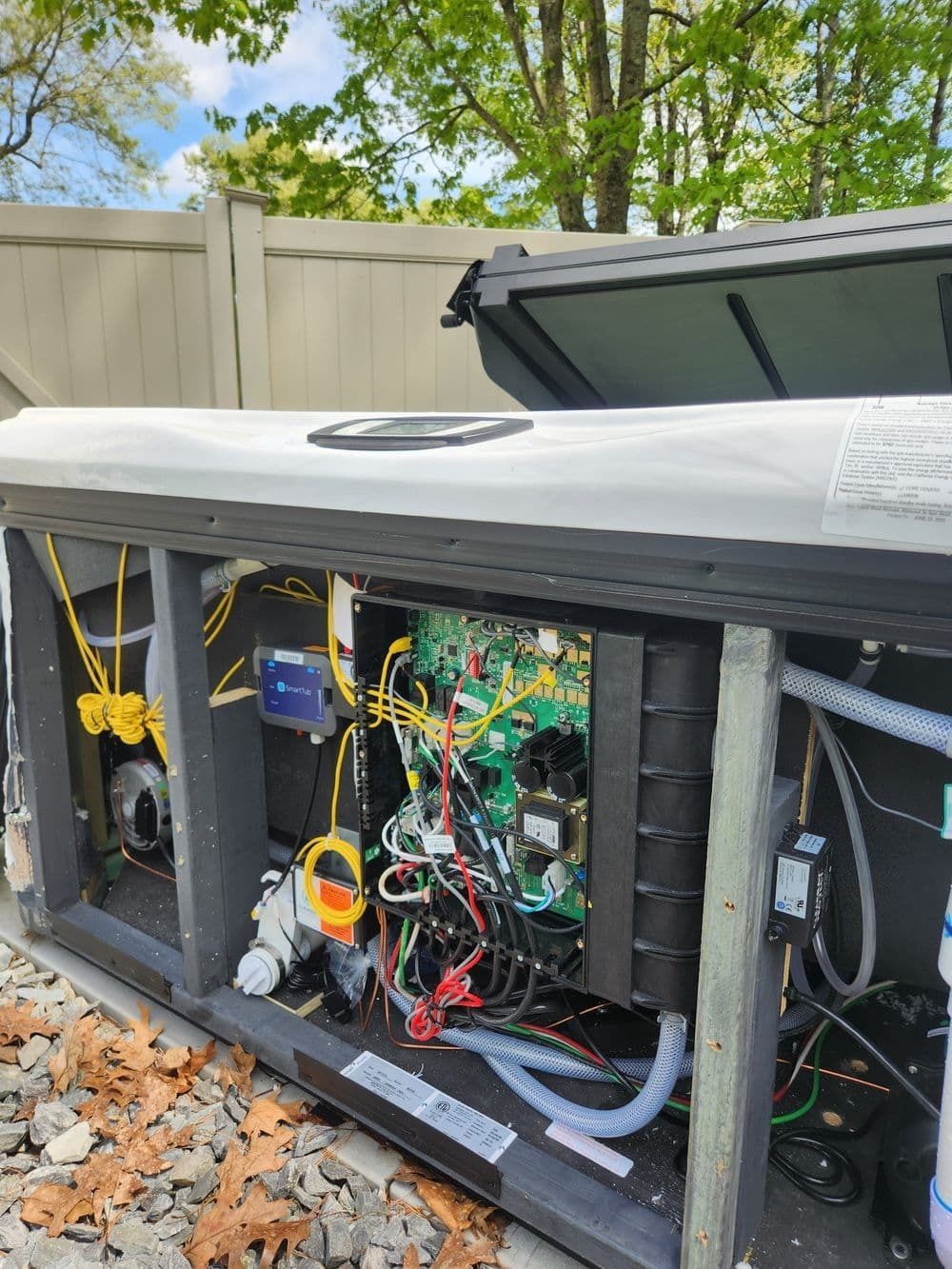Open view of a hot tub's internal components. Wiring, circuits, and a control panel are visible within the tub's frame.