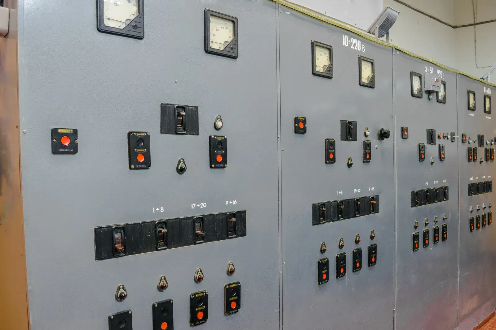 Gray electrical control panel with switches, gauges, and indicators.