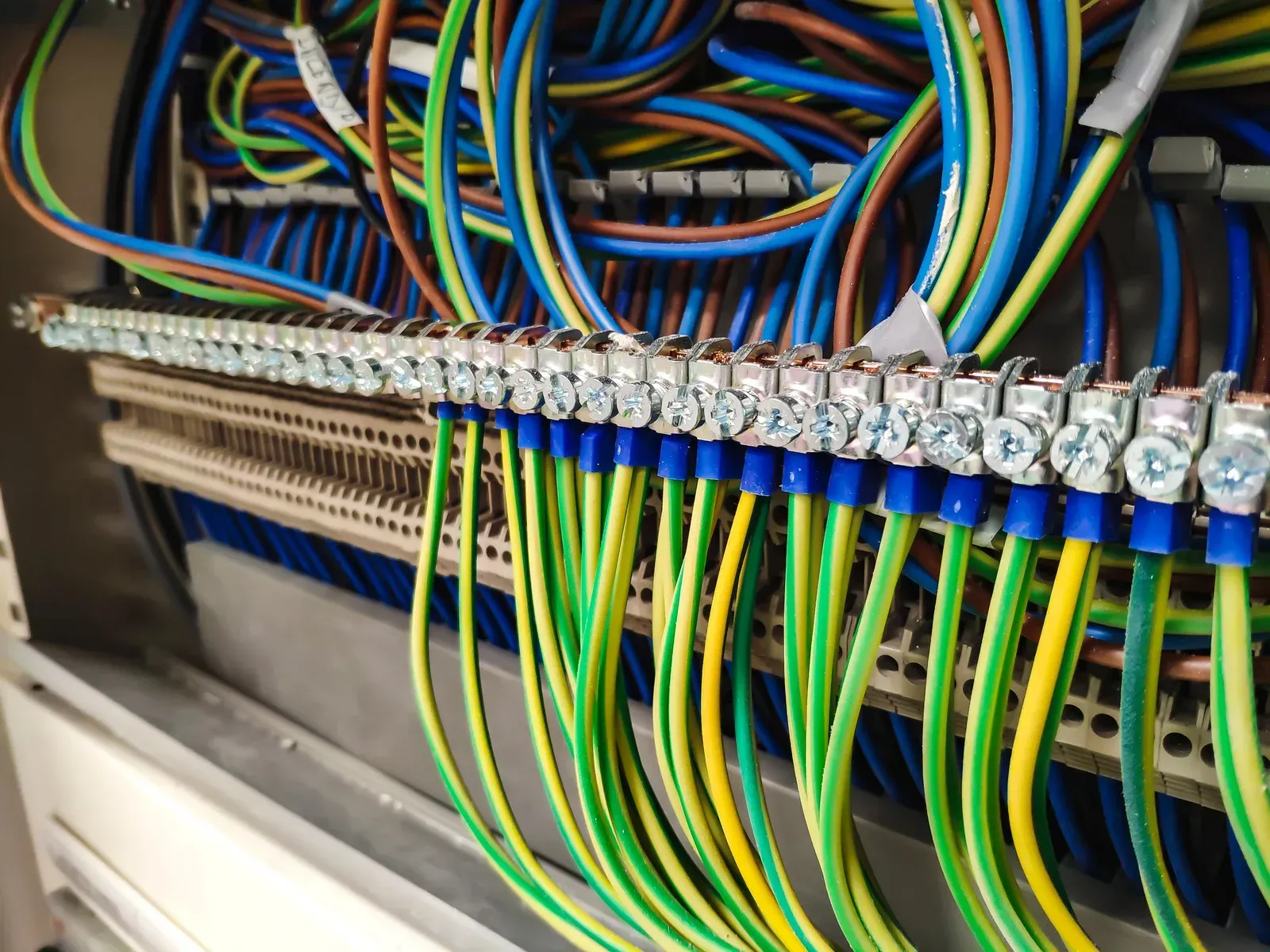 Electrical panel with numerous wires connected to grounding bar. Green/yellow ground wires prominent.
