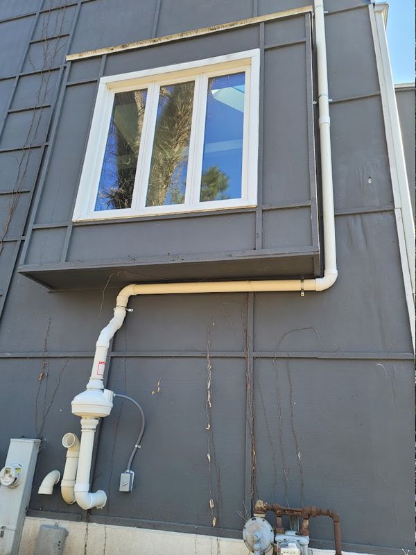 A window on the side of a building with pipes attached to it