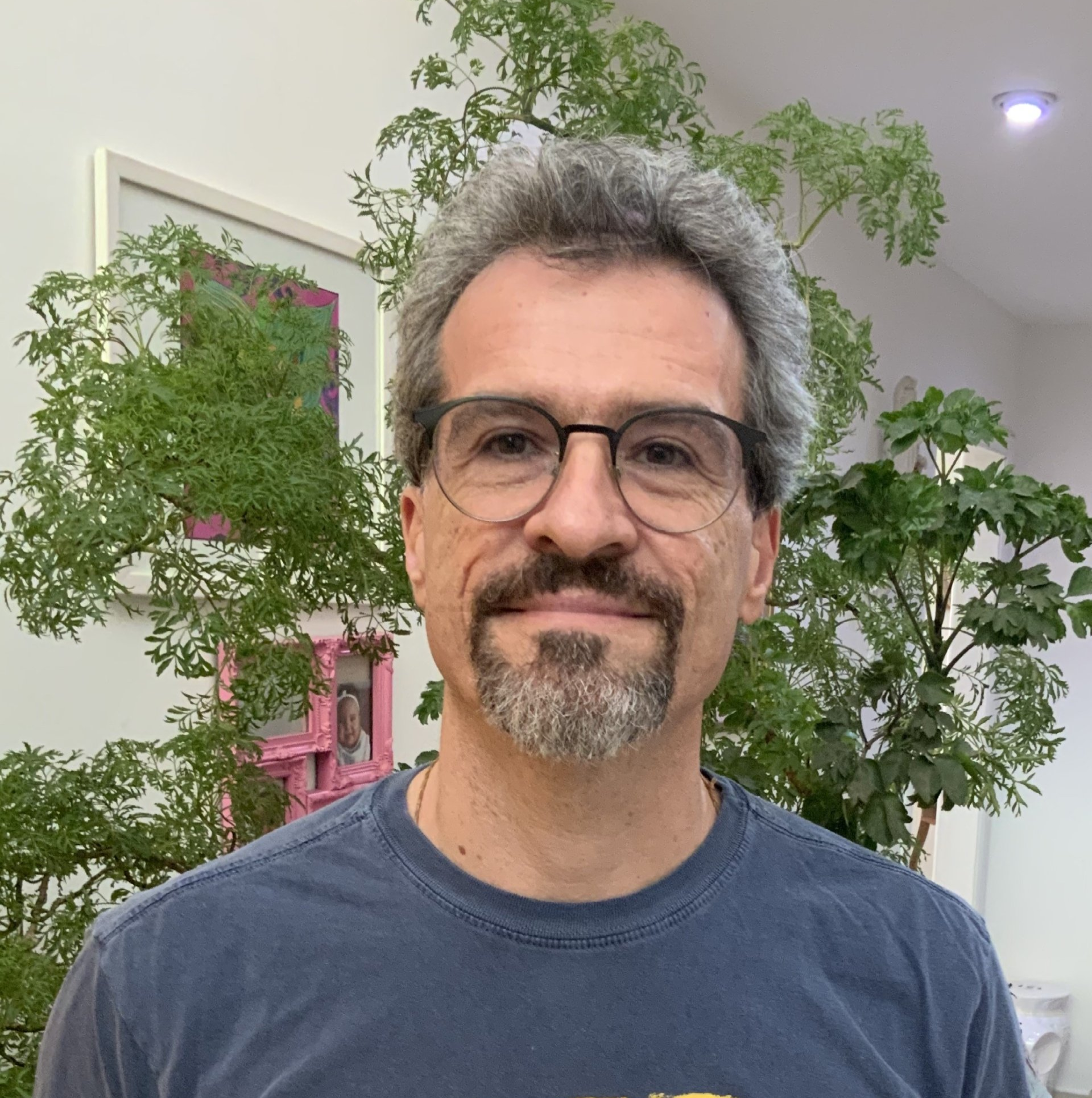 A man with glasses and a beard is wearing a blue shirt.