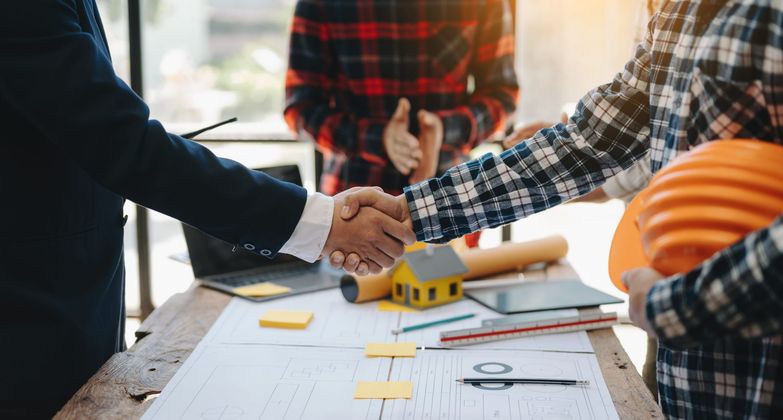 a group of construction workers are shaking hands over a table