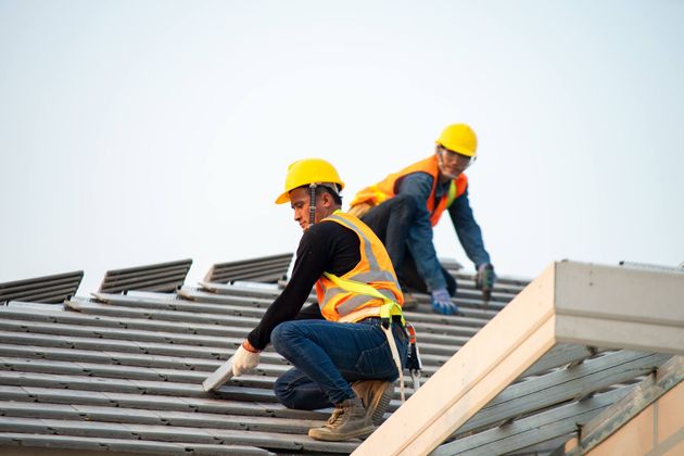 two construction workers are working on the roof of a building