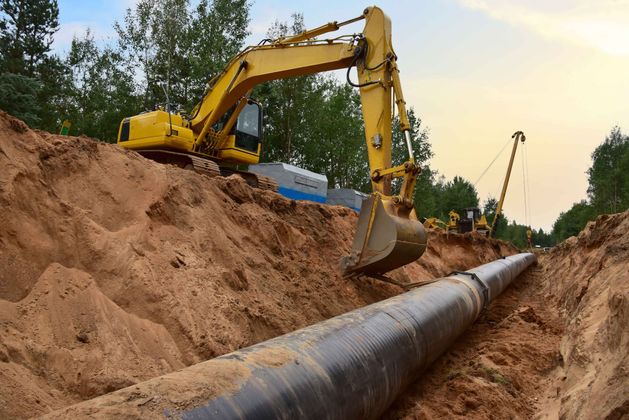 a yellow excavator is digging a hole for a pipe