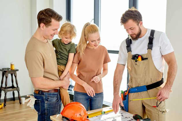 a man is measuring a piece of wood with a tape measure while a family looks on