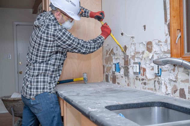 a man is working on a kitchen counter with a hammer and measuring tape