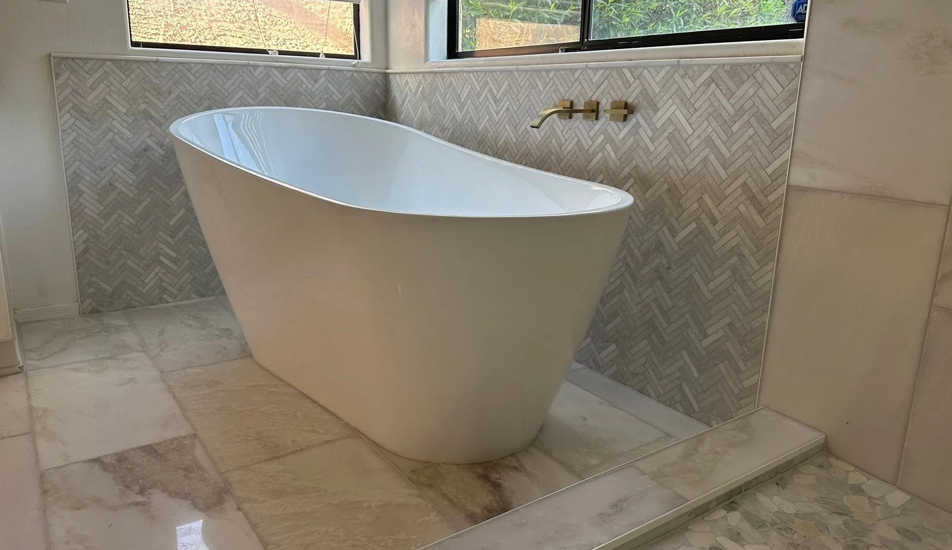 A white bathtub is sitting in a bathroom next to a window.