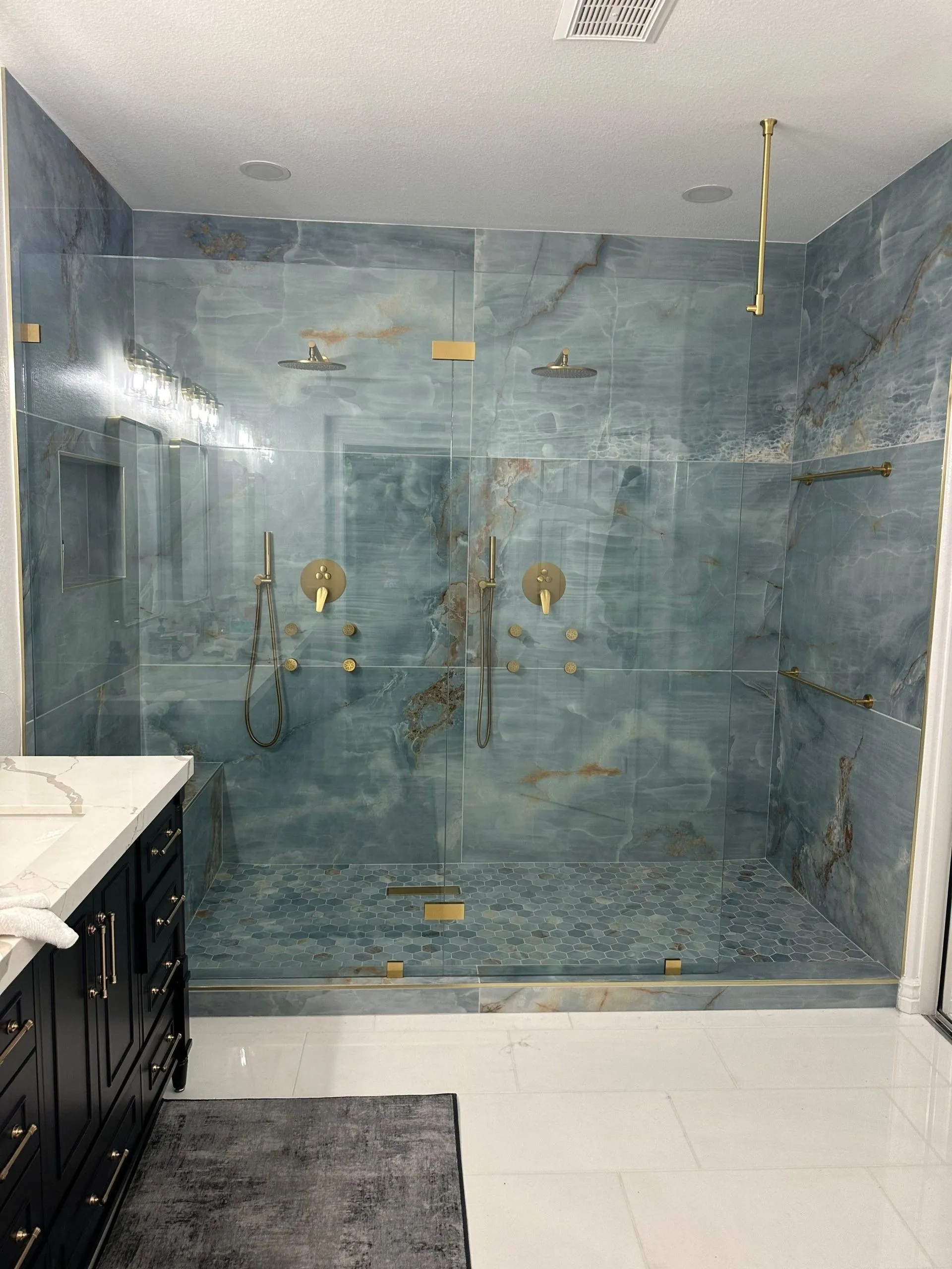 A bathroom with a walk in shower and a sink.