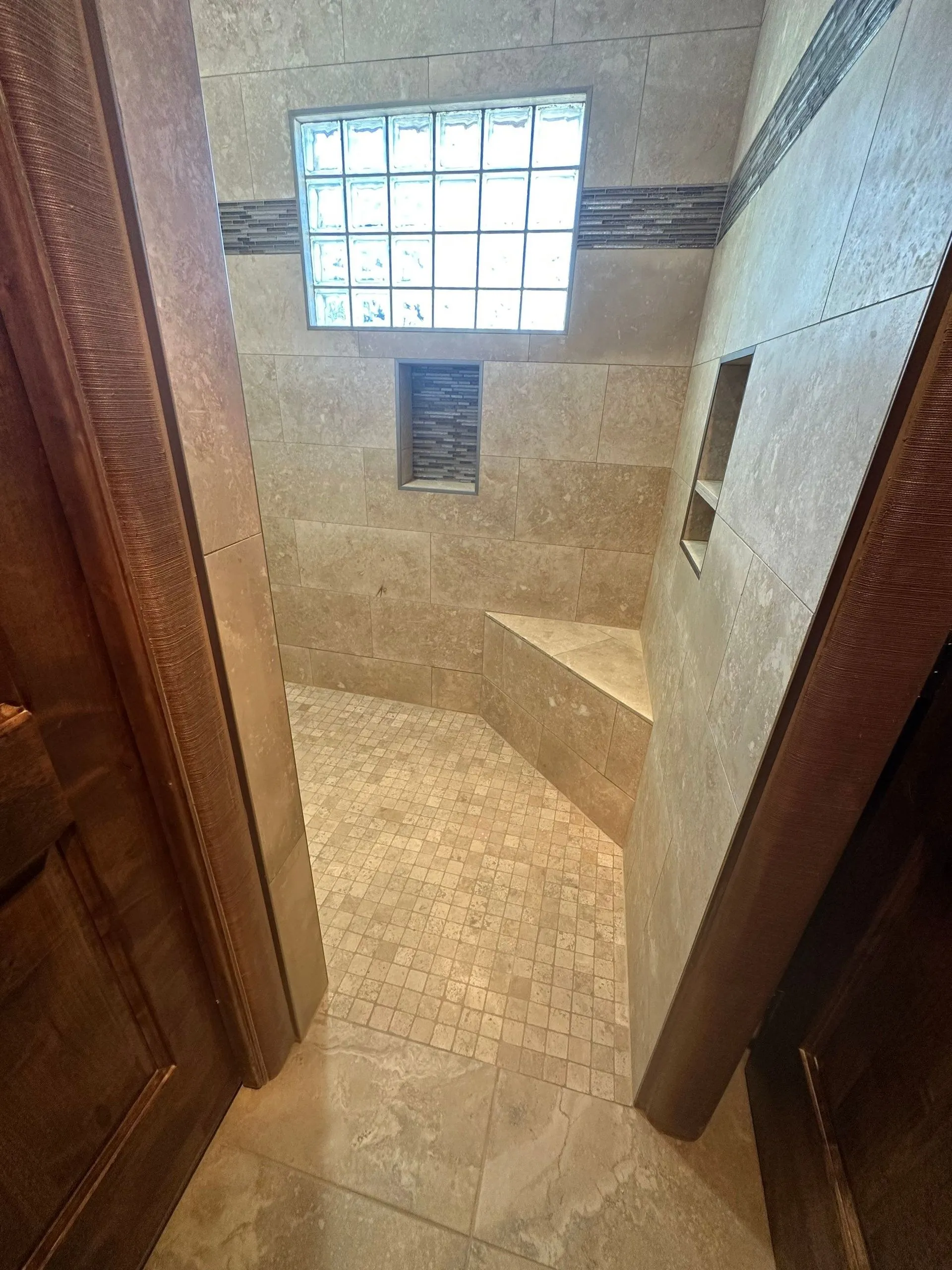 A bathroom with a walk in shower and a glass block window.