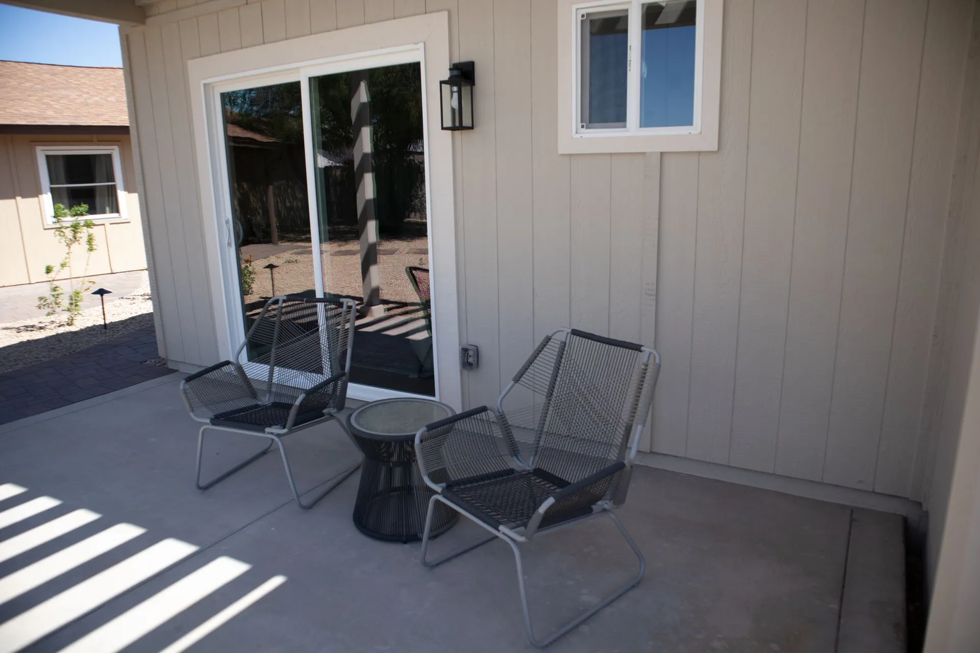 A patio with chairs and a table in front of a sliding glass door.