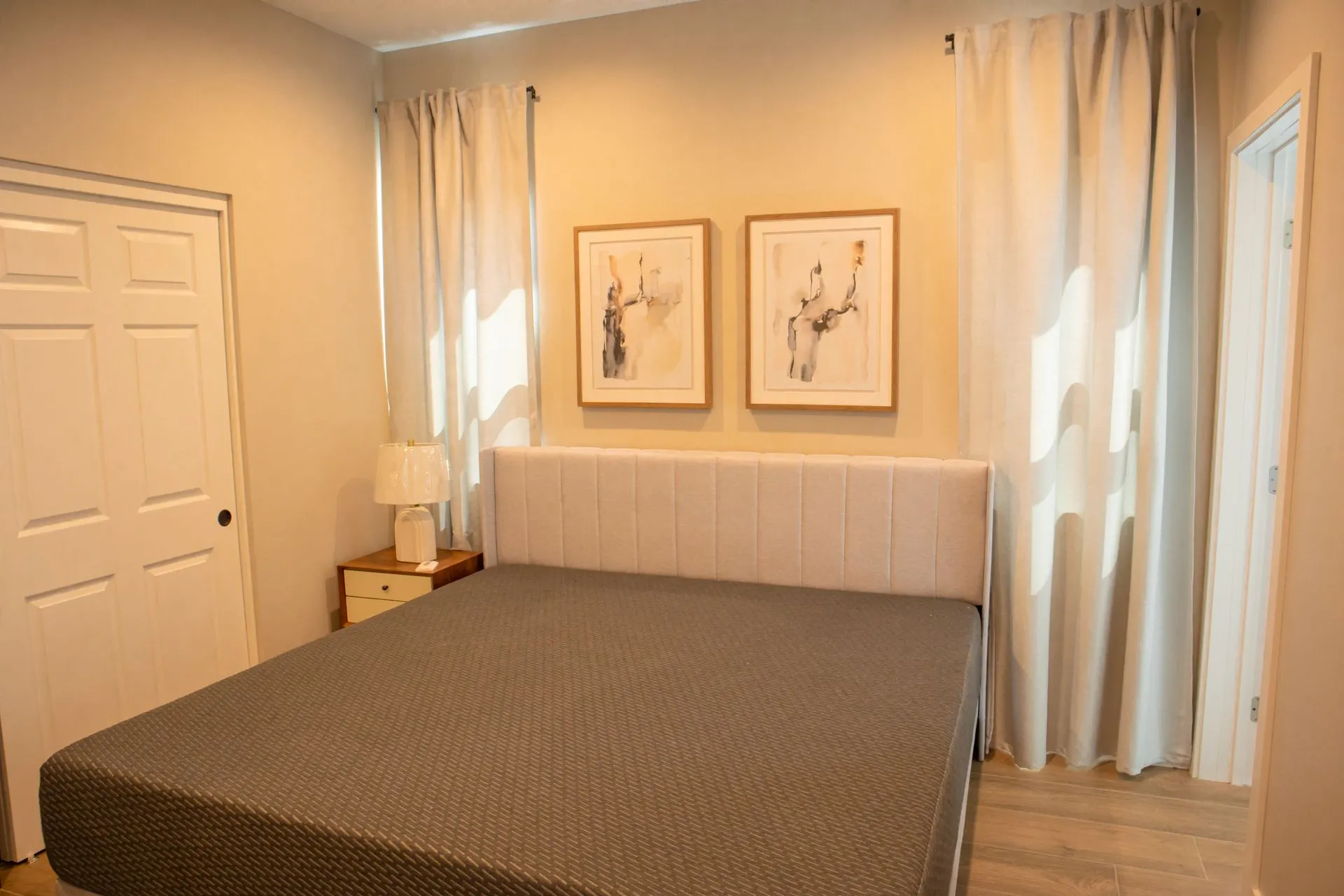 A bedroom with a bed , two lamps , and two pictures on the wall.