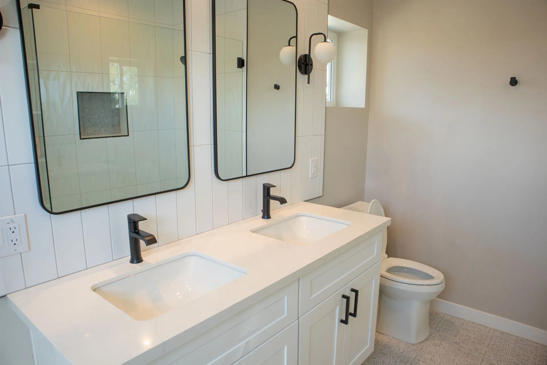 A bathroom with two sinks , a toilet , and two mirrors.