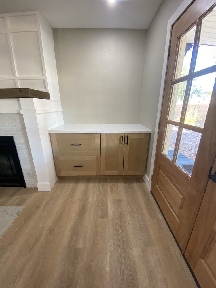 A living room with hardwood floors , cabinets , a fireplace and a door.