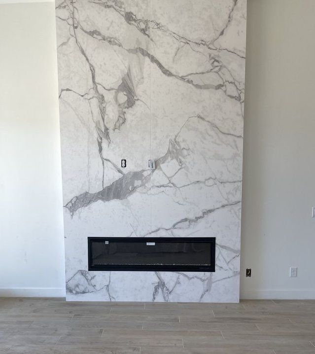 A fireplace in a living room with a marble wall