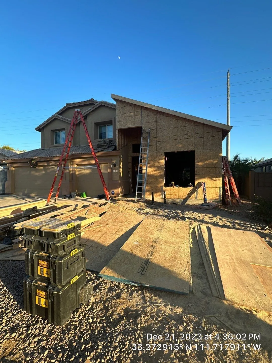 A house is being built with a ladder in the backyard.