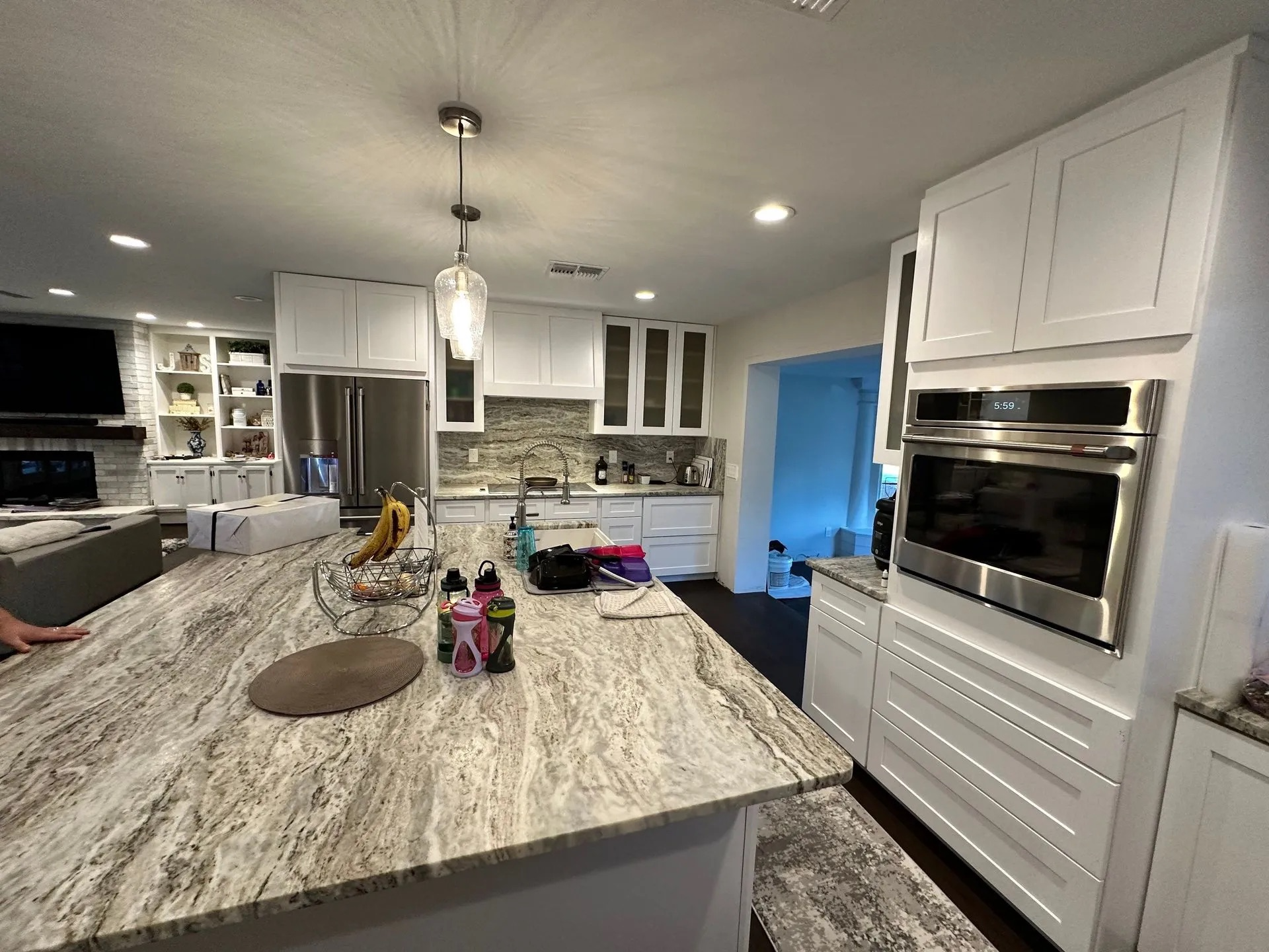 A kitchen with granite counter tops , white cabinets , and stainless steel appliances.