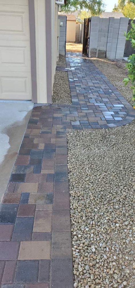 A sidewalk with bricks and gravel next to a garage door.