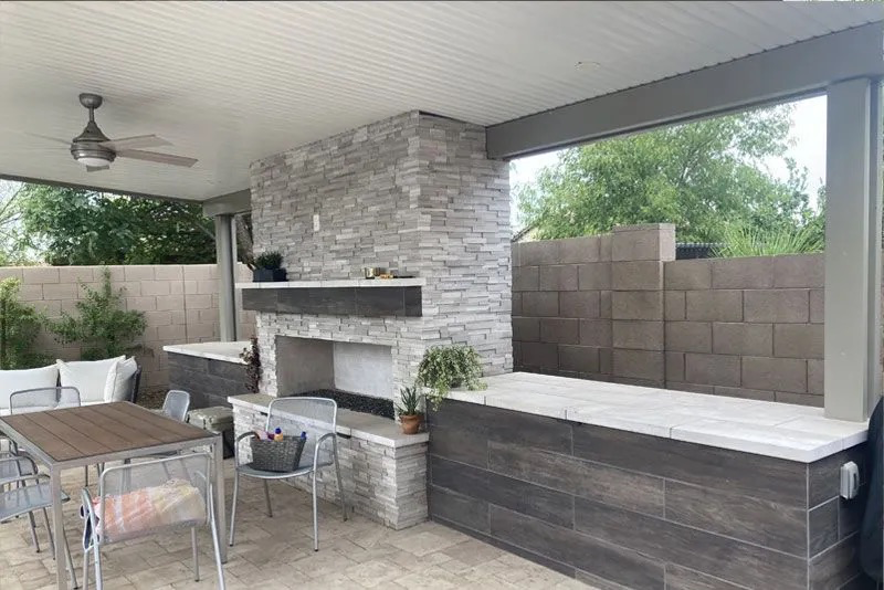 A patio with a table and chairs and a fireplace.