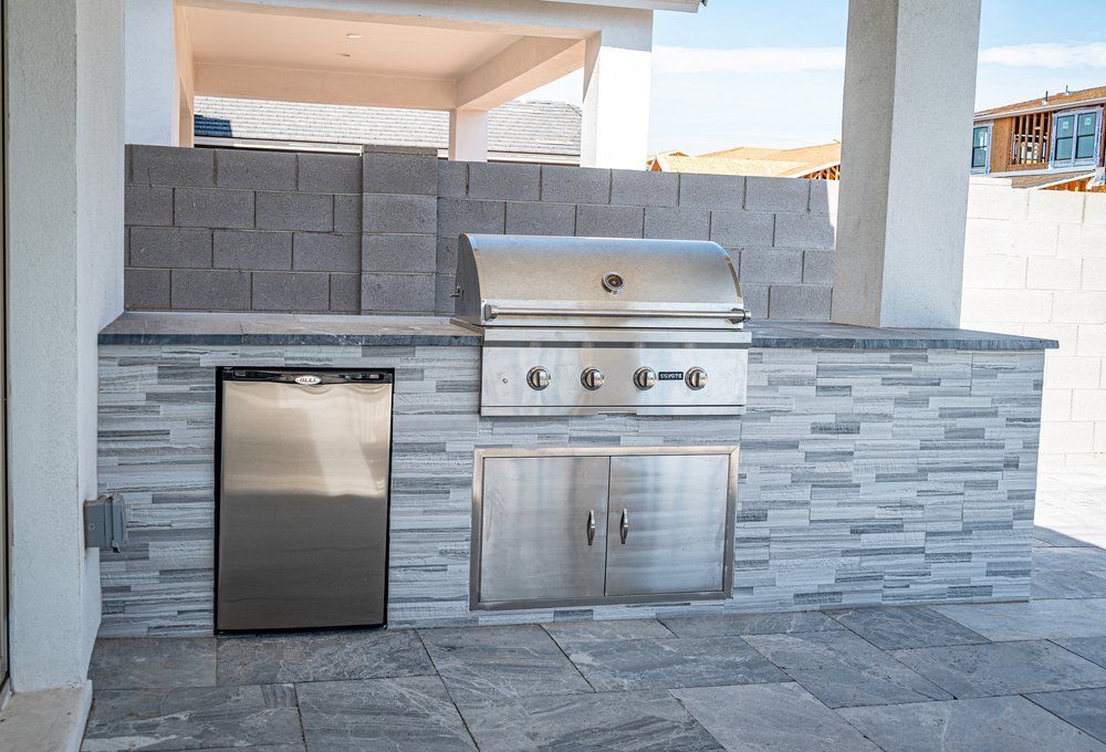A stainless steel grill is built into a stone wall.