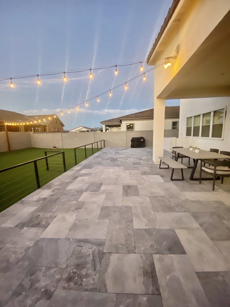 A large patio with a table and chairs and a string of lights hanging from the ceiling.