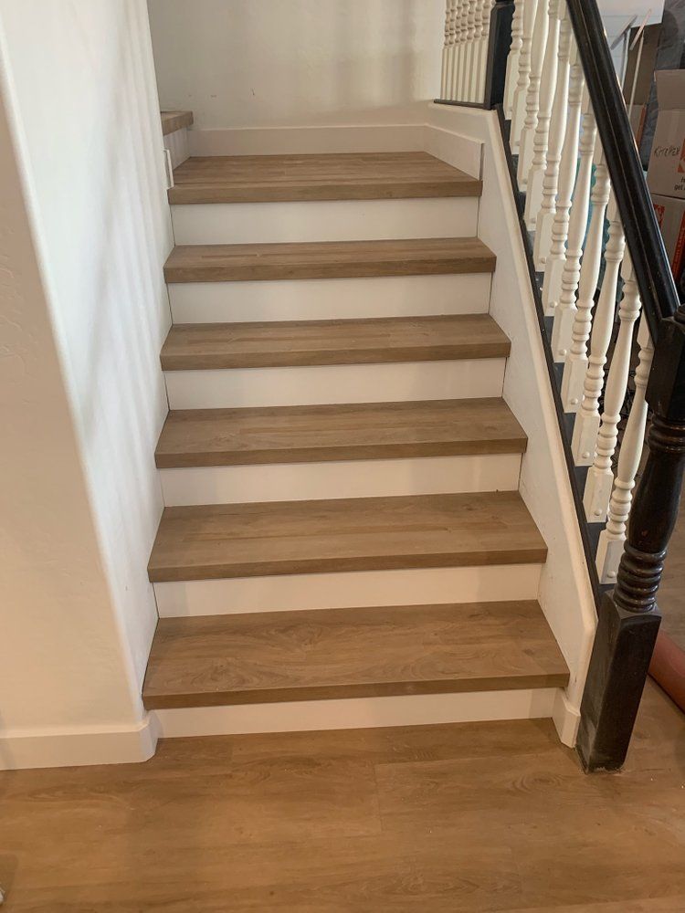 A wooden staircase with white steps and a black railing in a house.