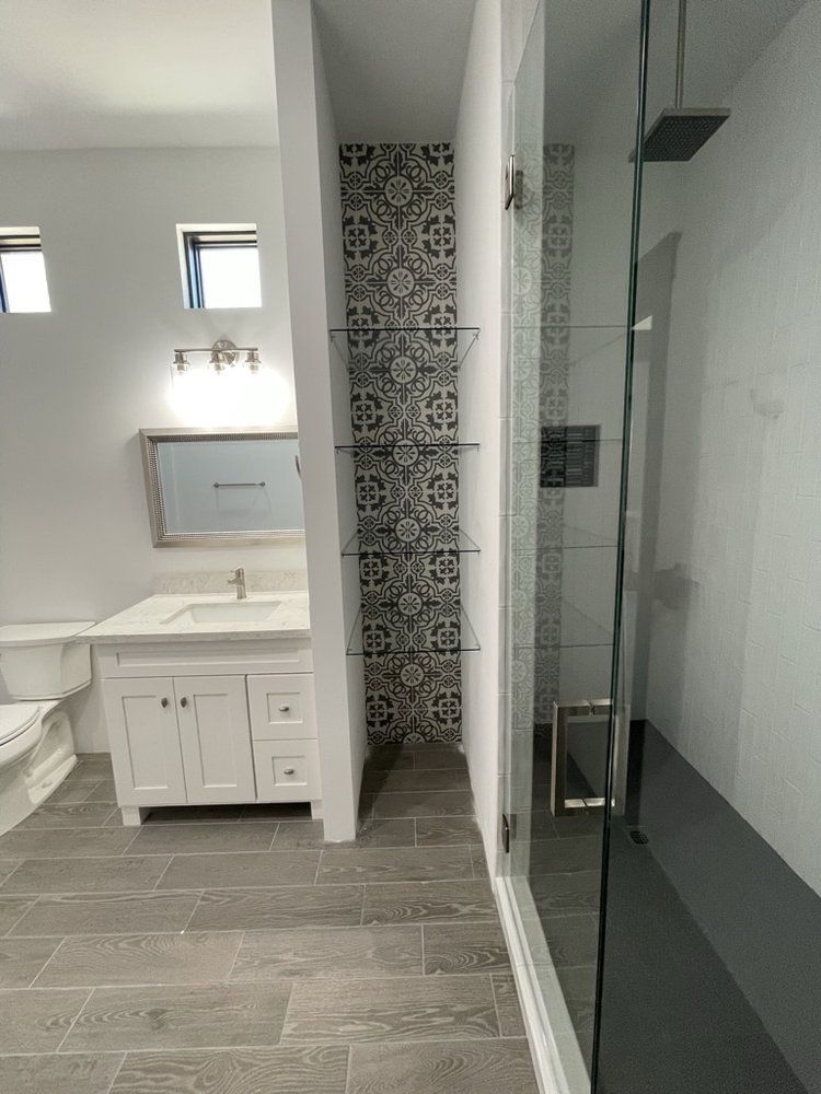 A bathroom with a sink , toilet , shower and mirror.
