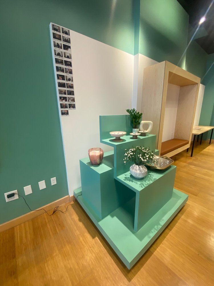 A display of vases and bowls on a green shelf in a room.
