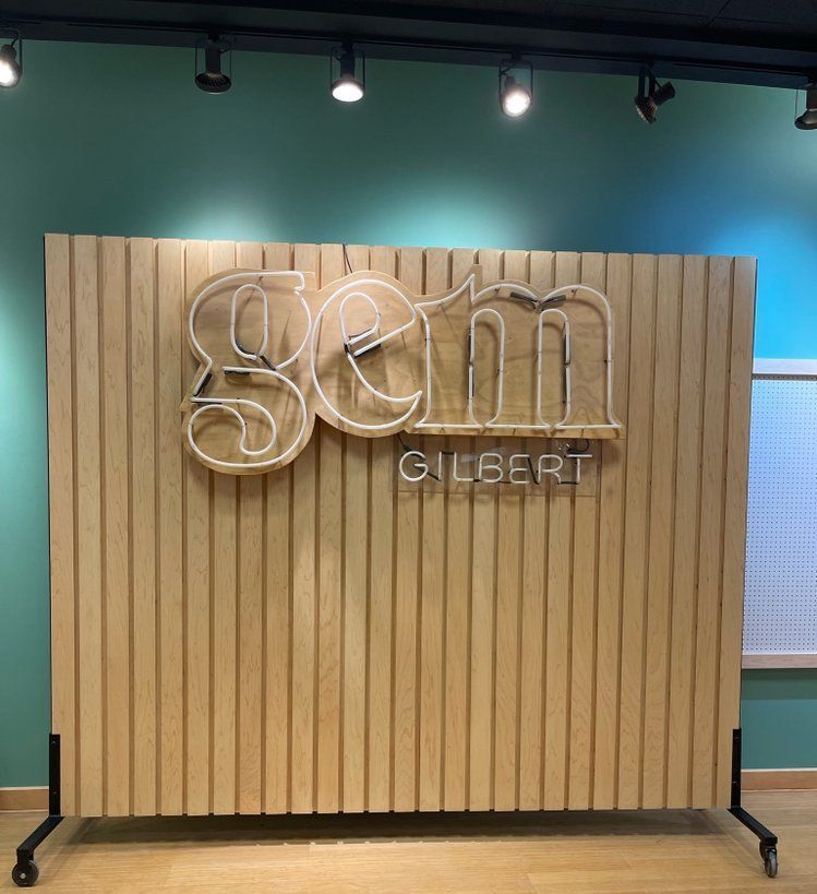 A wooden wall with a neon sign that says gilbert on it.