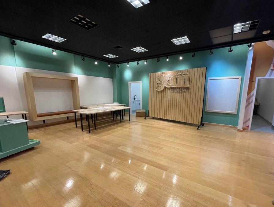 A large empty room with wooden floors and tables.