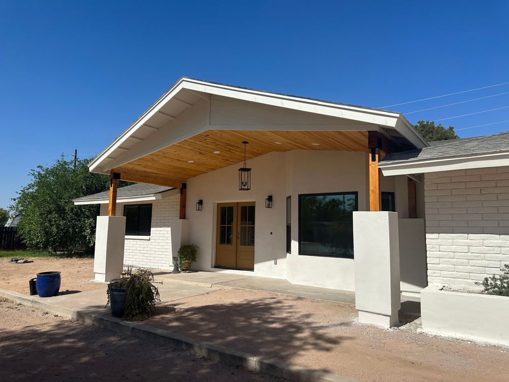 A white house with a wooden porch and a blue sky in the background.