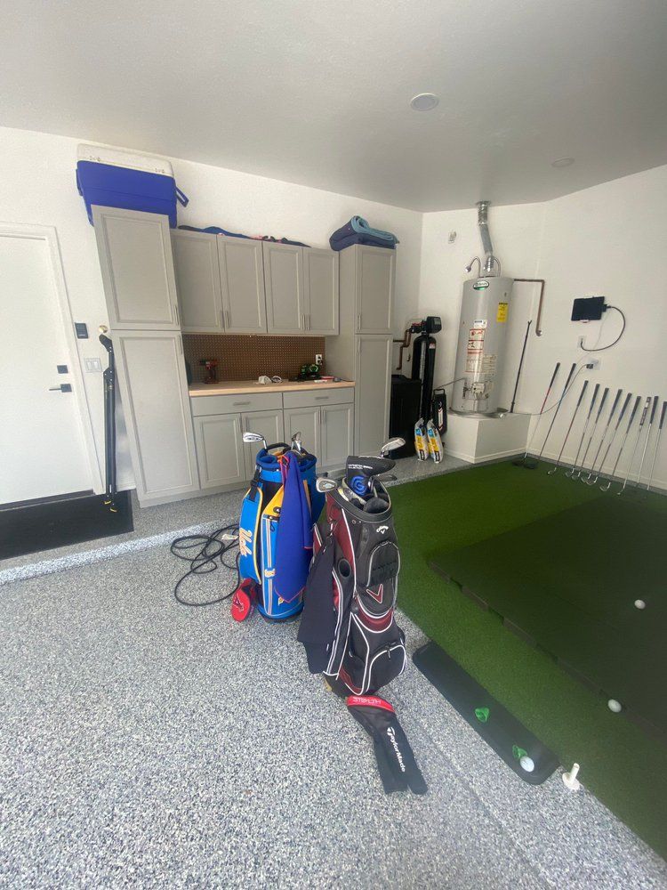 A golf bag is sitting in a garage next to a putting green.