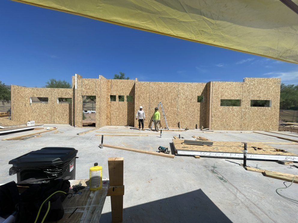 Two men are standing in front of a building under construction.