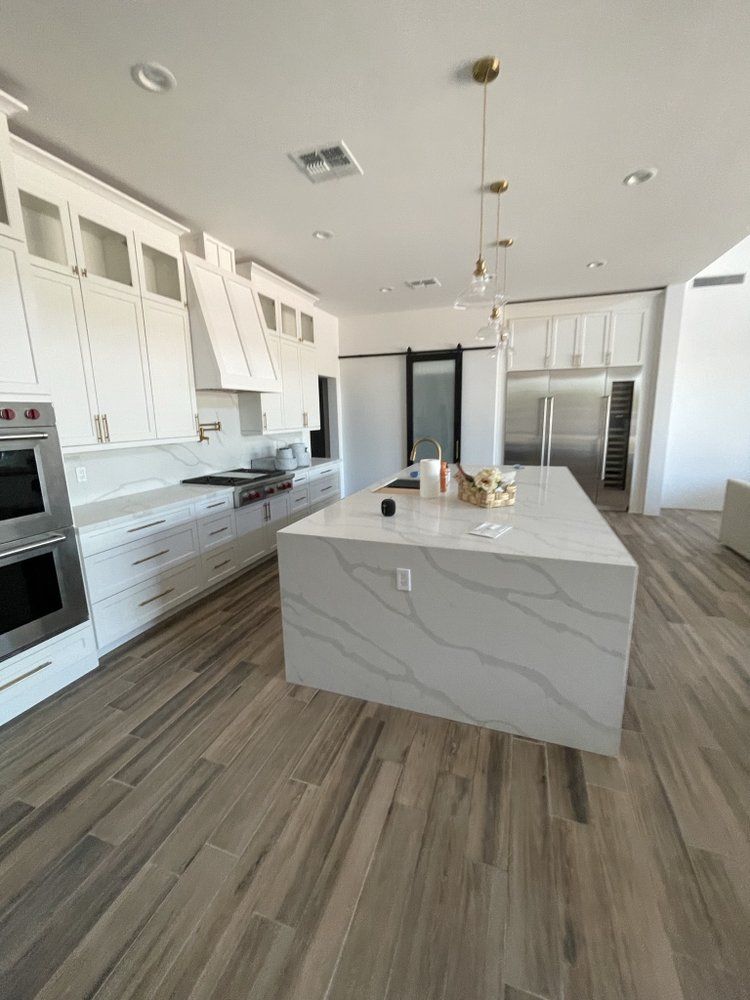 A kitchen with white cabinets and a large island in the middle.