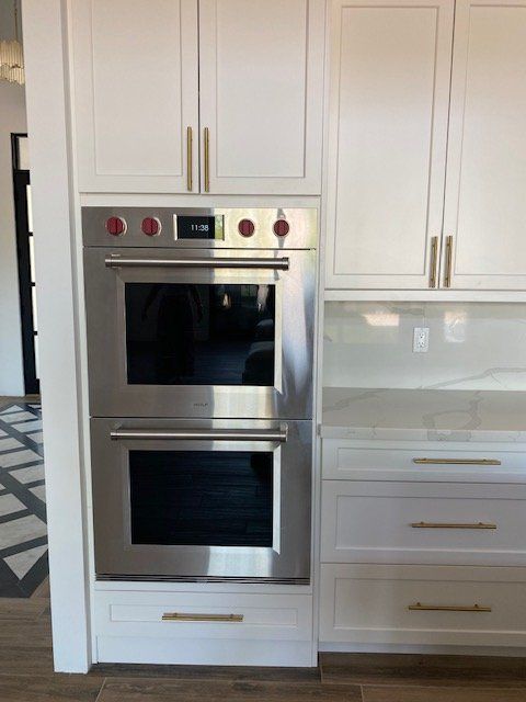 A stainless steel double oven in a kitchen with white cabinets