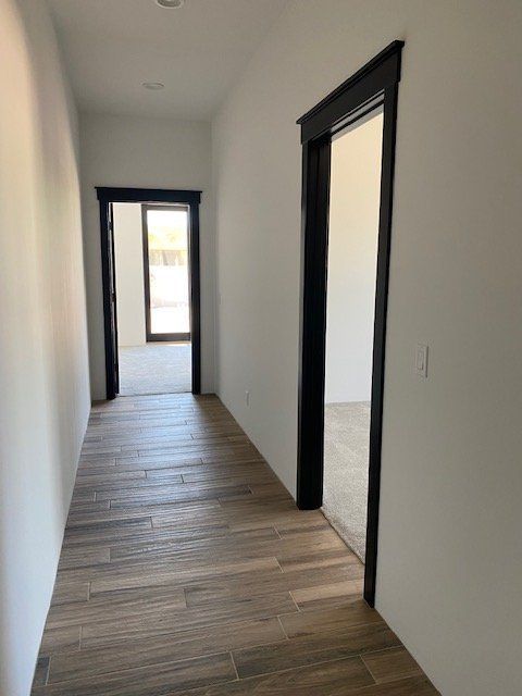 A long hallway with wooden floors and two doors leading to different rooms.