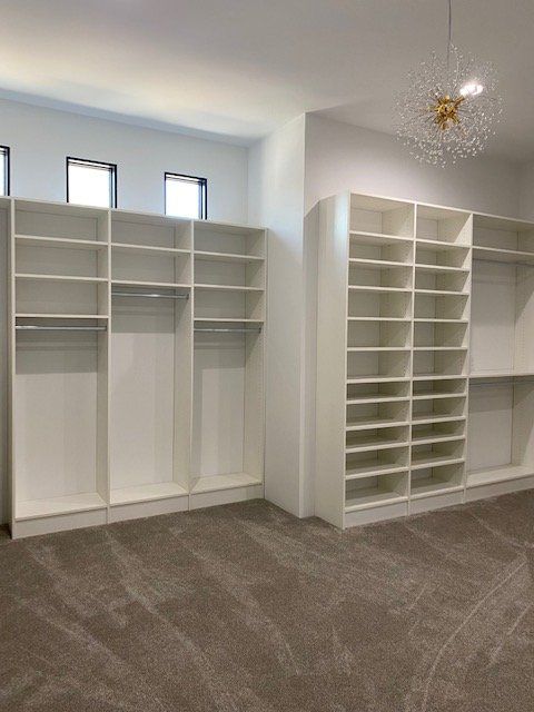 A walk in closet with lots of shelves and a chandelier hanging from the ceiling.