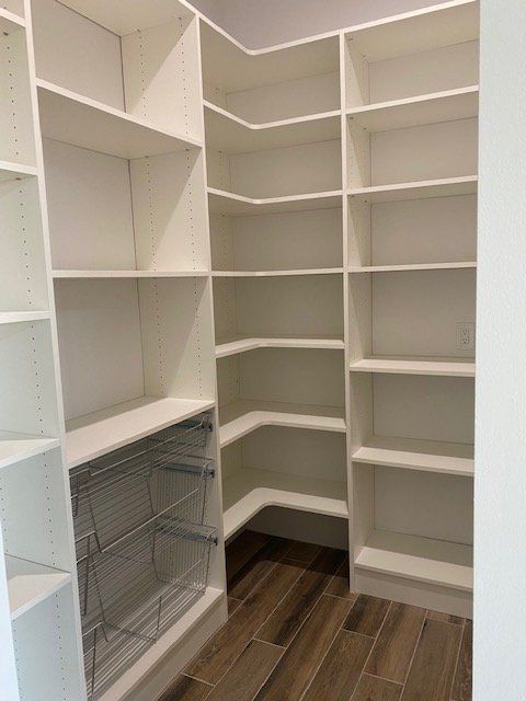 A walk in pantry with lots of shelves and baskets.