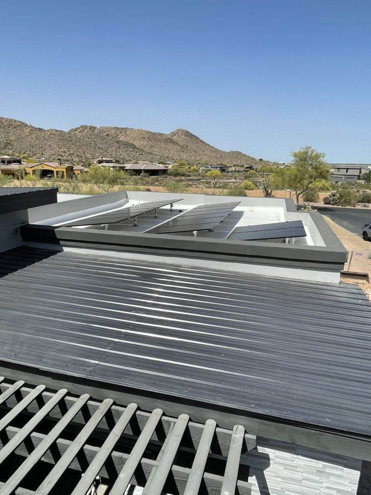 A roof with a lot of solar panels on it and mountains in the background.