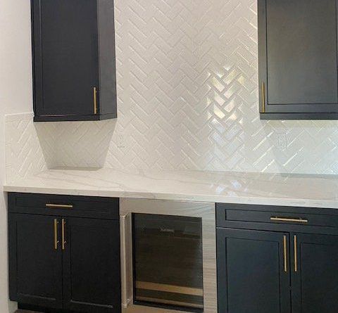 A kitchen with black cabinets and a wine cooler.