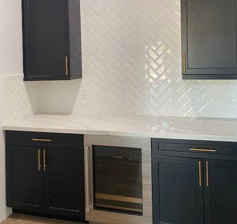 A kitchen with black cabinets and a wine cooler.