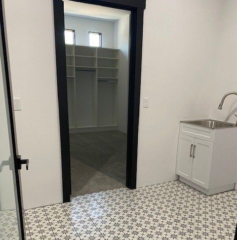 A laundry room with a sink , cabinets , and shelves.
