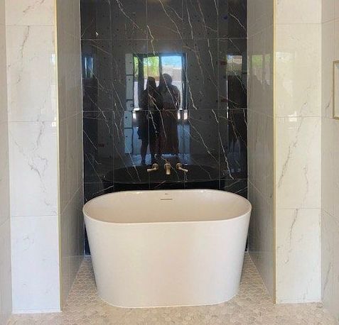 A white bathtub is sitting in a bathroom next to a mirror.
