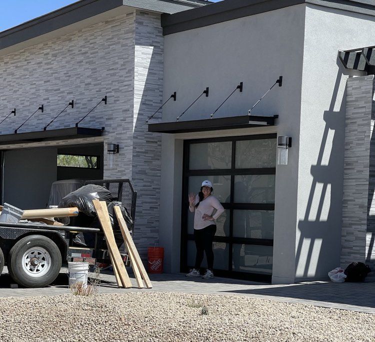 A woman is standing in front of a house with a truck parked in front of it.
