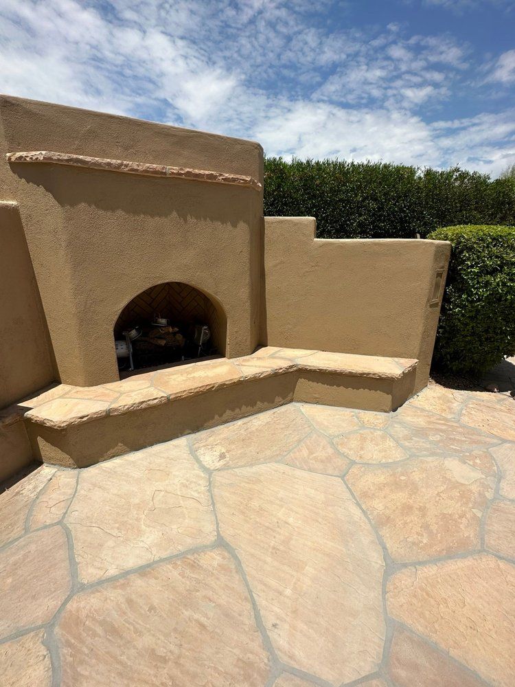 A fireplace with a bench in front of it on a patio.