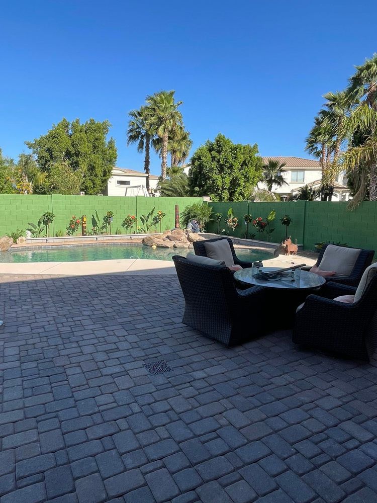 A patio with a table and chairs next to a pool.