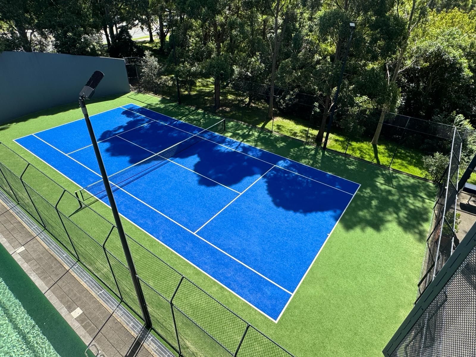 an aerial view of a blue tennis court surrounded by trees .